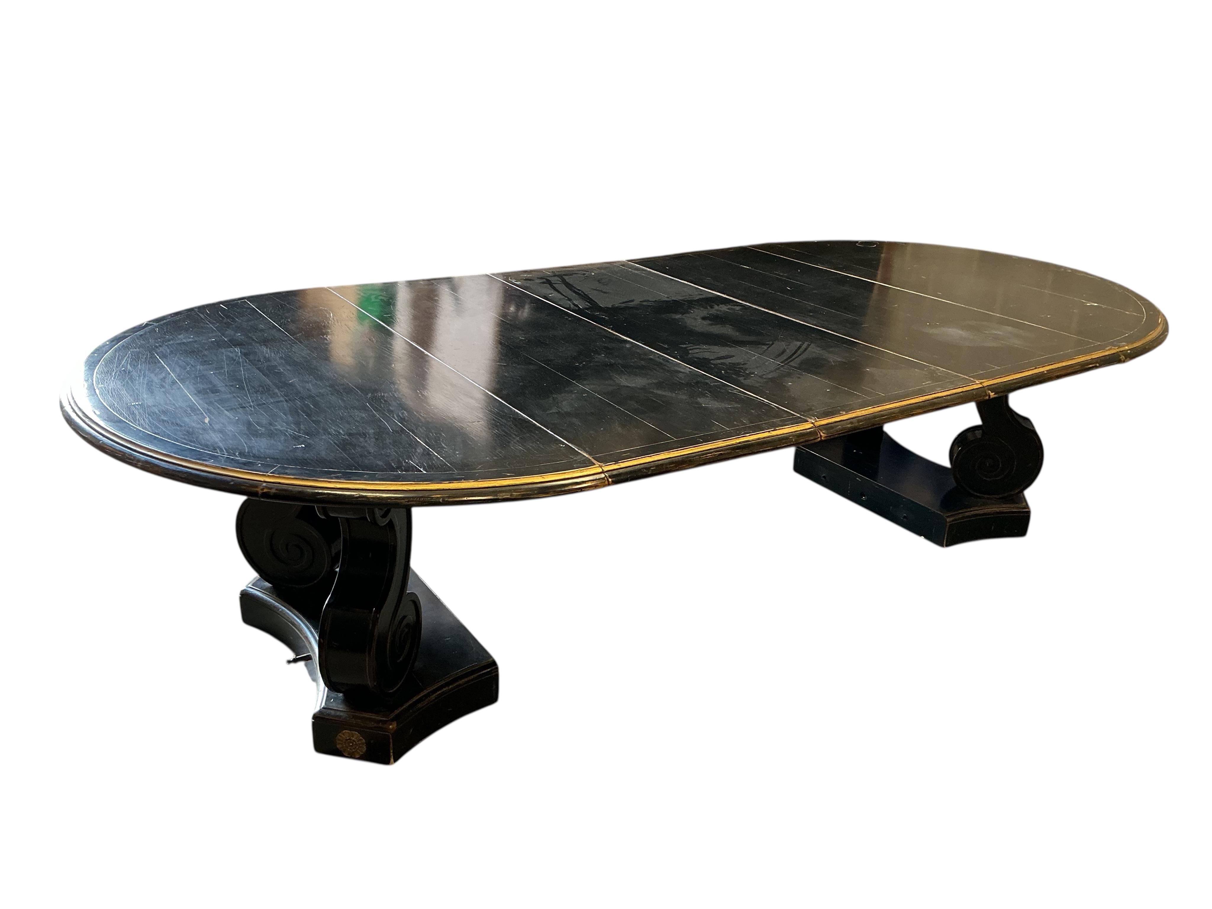 A Regency style ebonised, parcel gilt extending dining table, purchased from Liberty, diameter 150cm, 305cm extended three spare leaves, height
